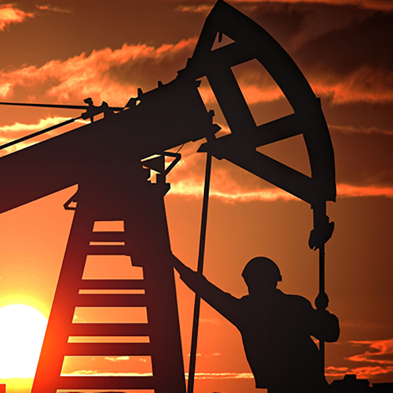 Silhouette of an oil rig and worker at sunset, highlighting the energy industry, oilfield operations, and industrial workforce in a dramatic evening sky.